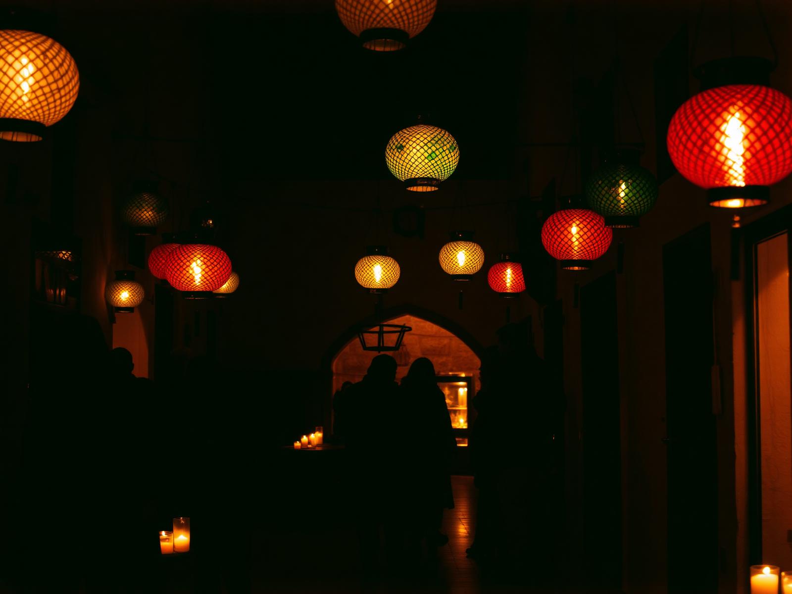 Lanterns and candlelight glowing in a Moroccan courtyard during an evening celebration